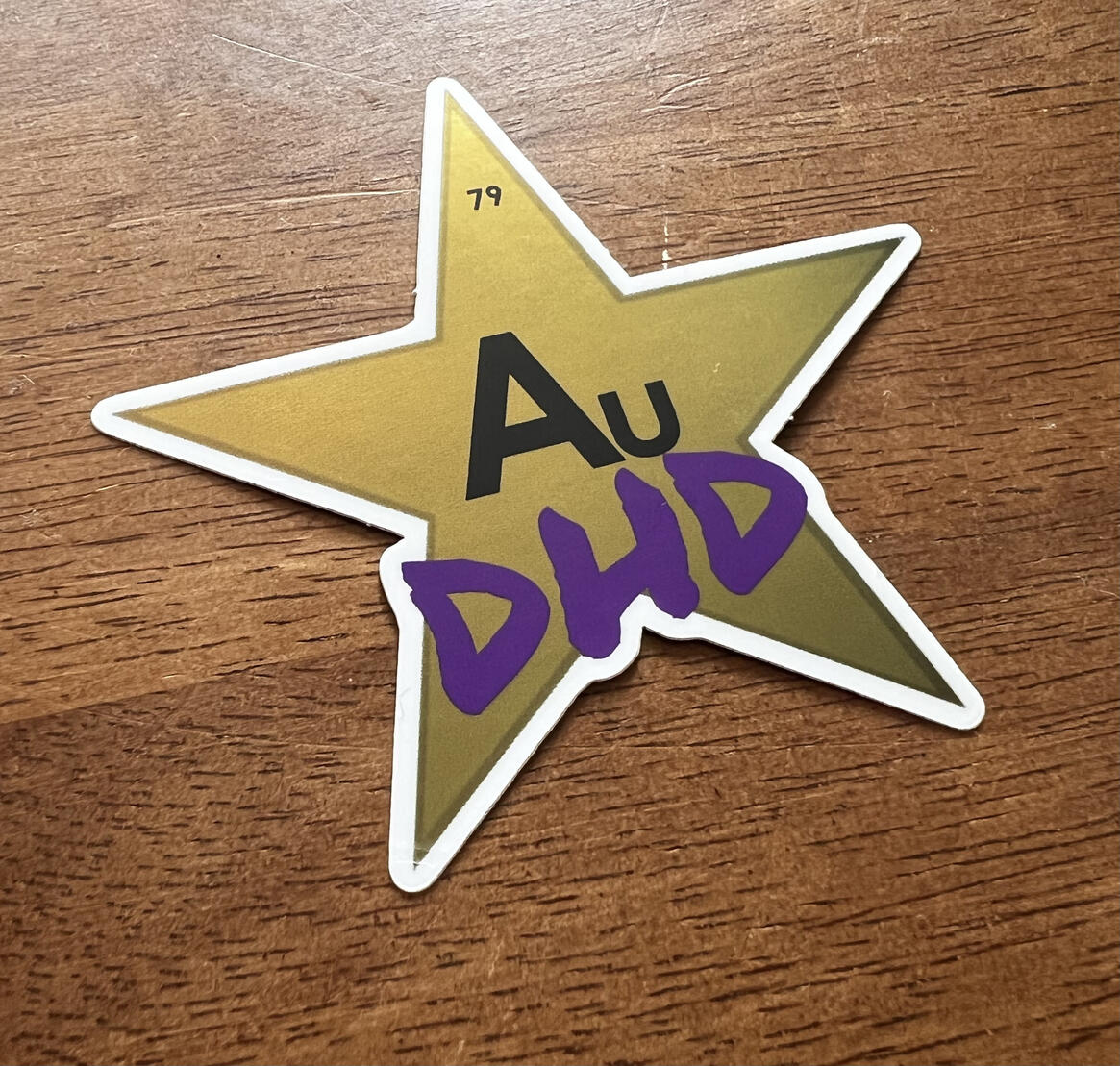 A metallic effect gold star with the number 79 at its tip, and text that reads "AuDHD."